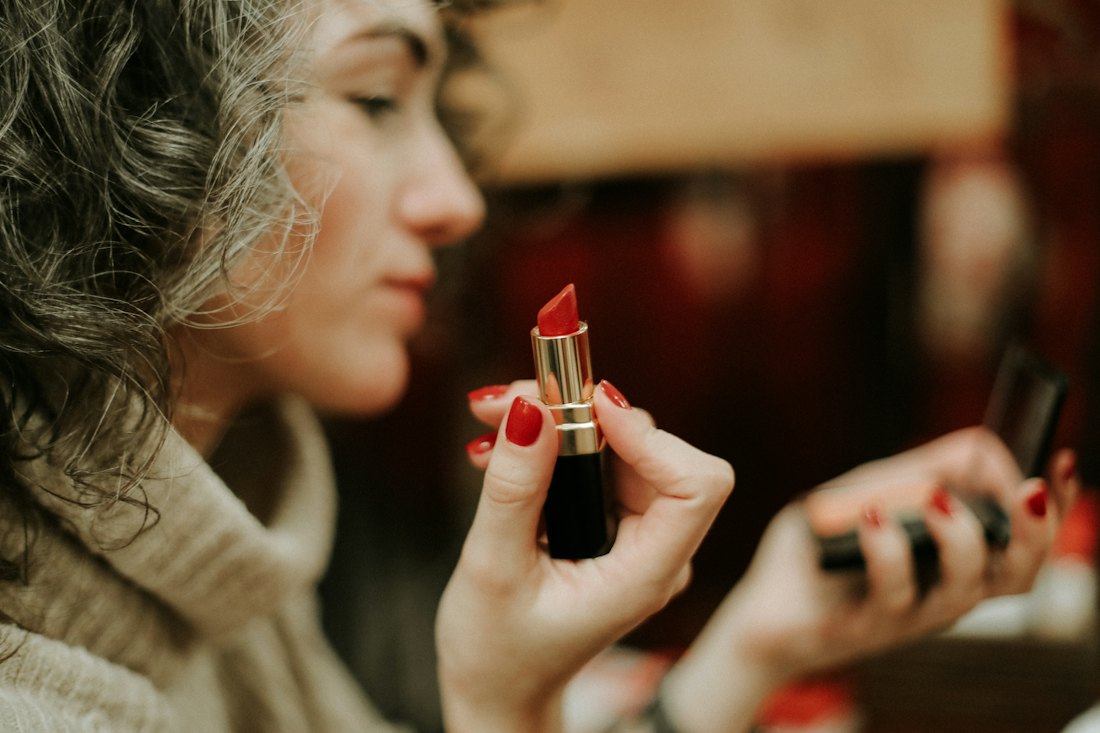 Frau trägt roten Lippenstift auf